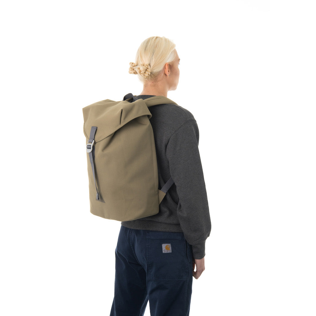 Woman carrying khaki flap backpack.