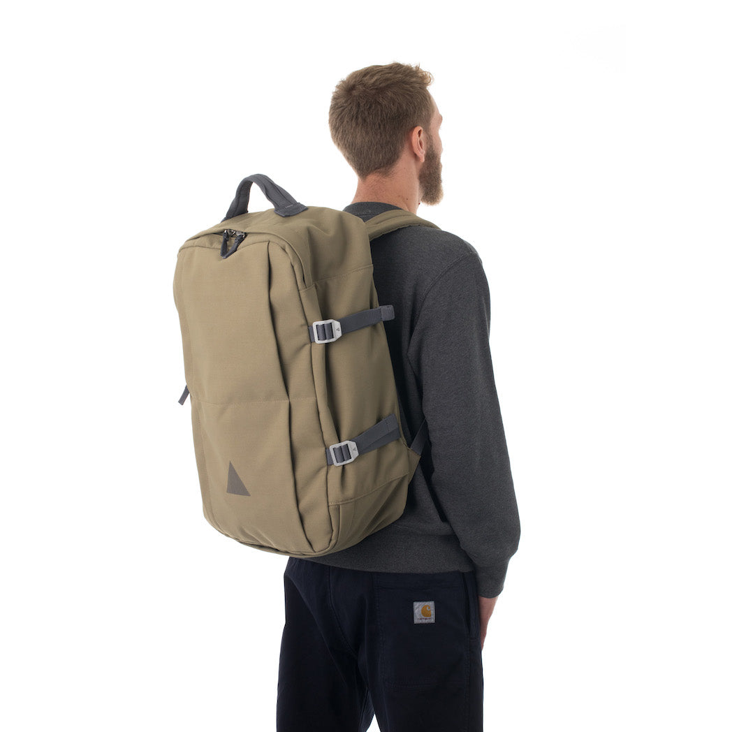 Man carrying khaki travel backpack.