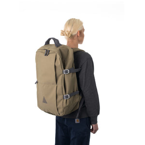 Woman carrying khaki travel backpack.
