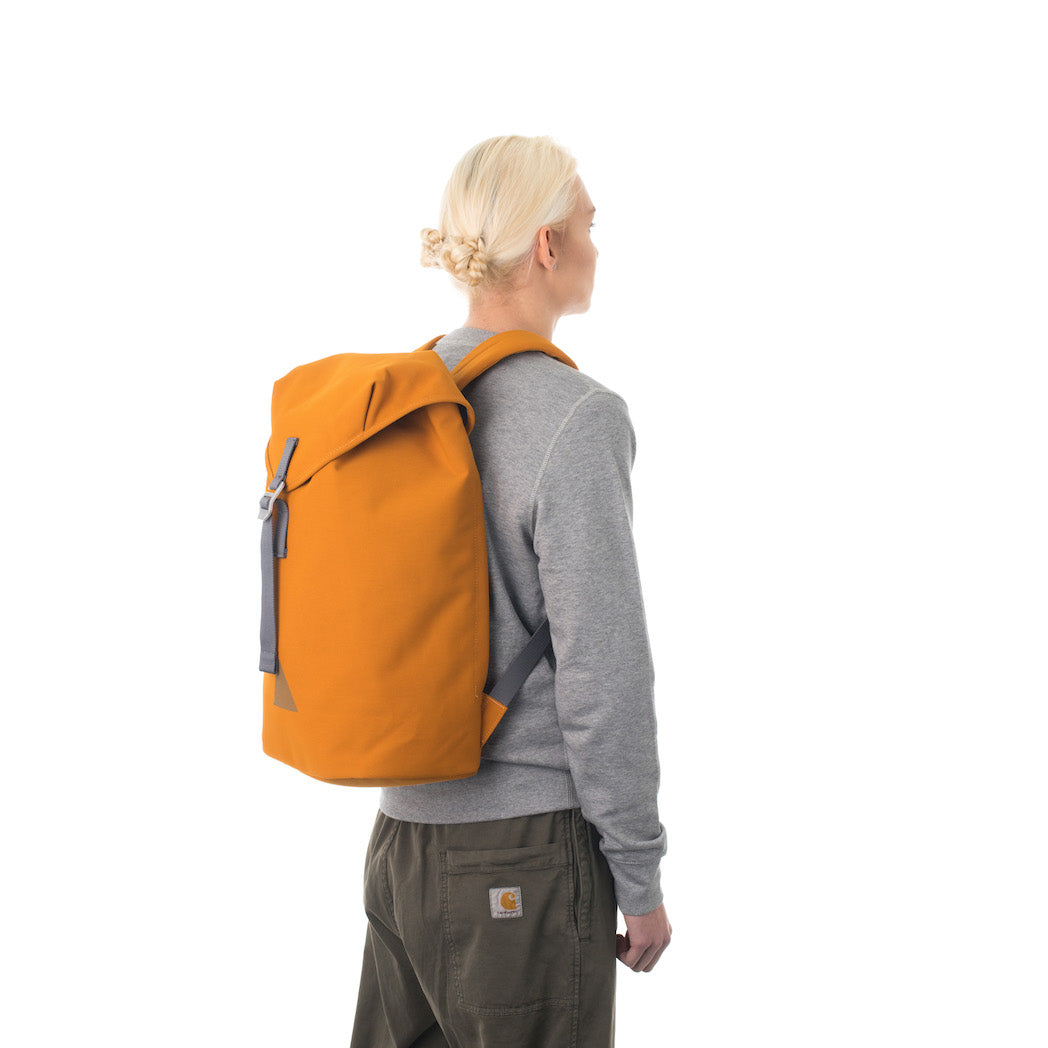 Woman carrying orange flap backpack.