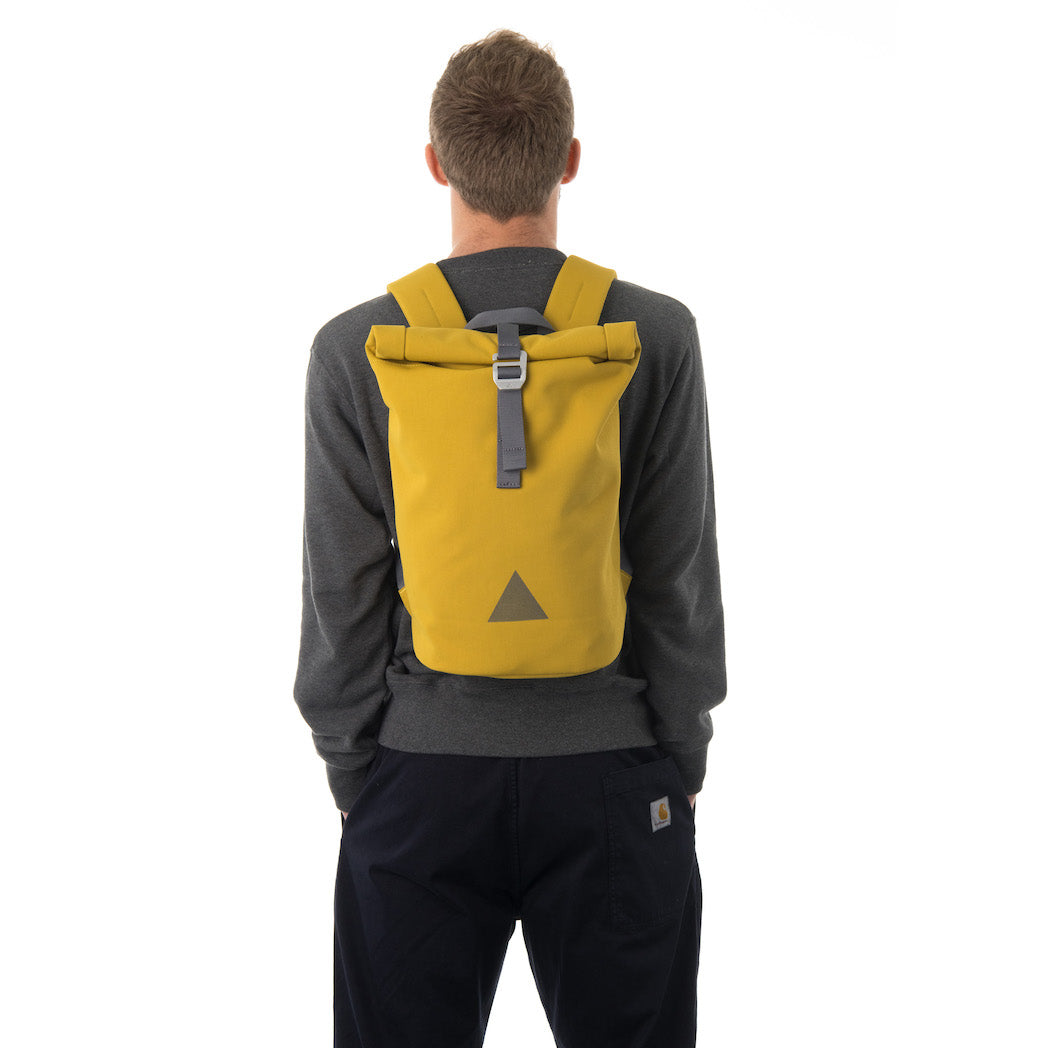 Man carrying yellow waterproof rolltop backpack.
