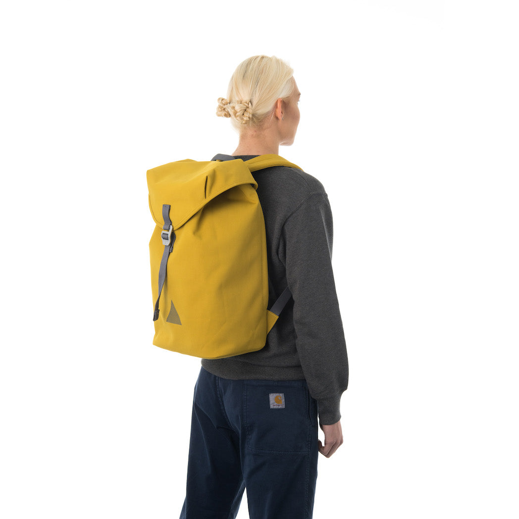 Woman carrying yellow flap backpack.