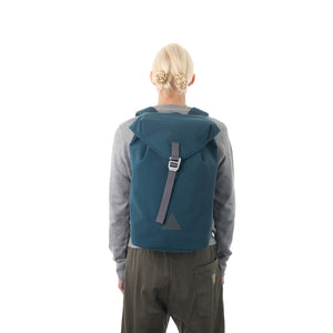 Woman carrying blue waterproof flap backpack.