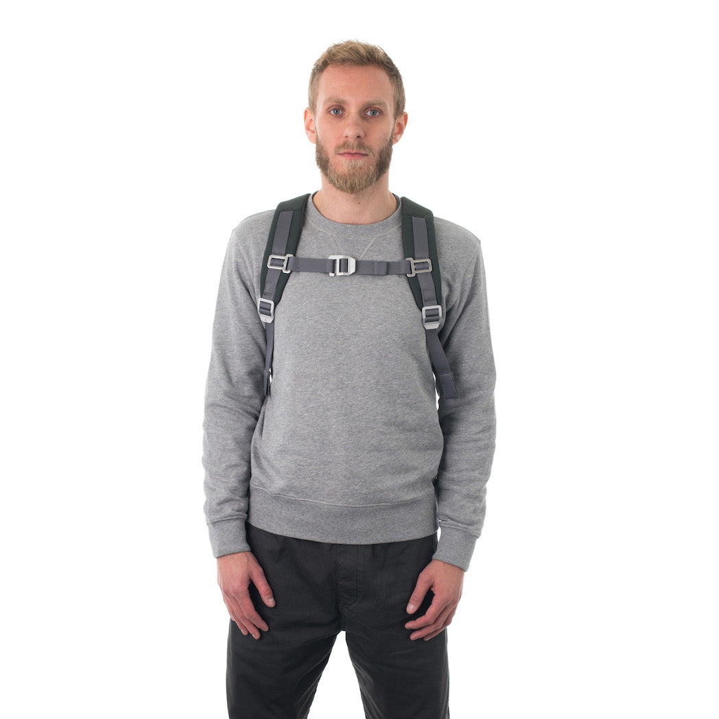 Man carrying grey flap backpack with padded shoulder straps.