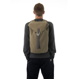 Man carrying khaki waterproof flap backpack.