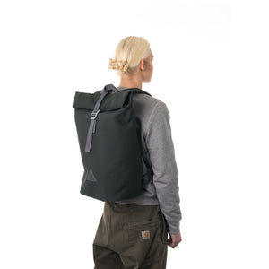 Woman carrying grey rolltop backpack.