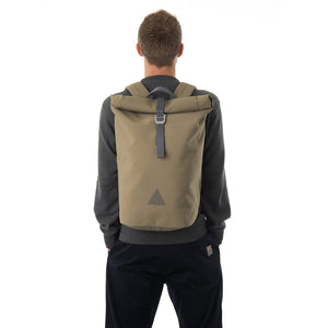Man carrying khaki waterproof rolltop backpack.