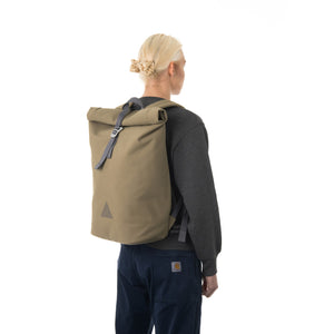 Woman carrying khaki rolltop backpack.