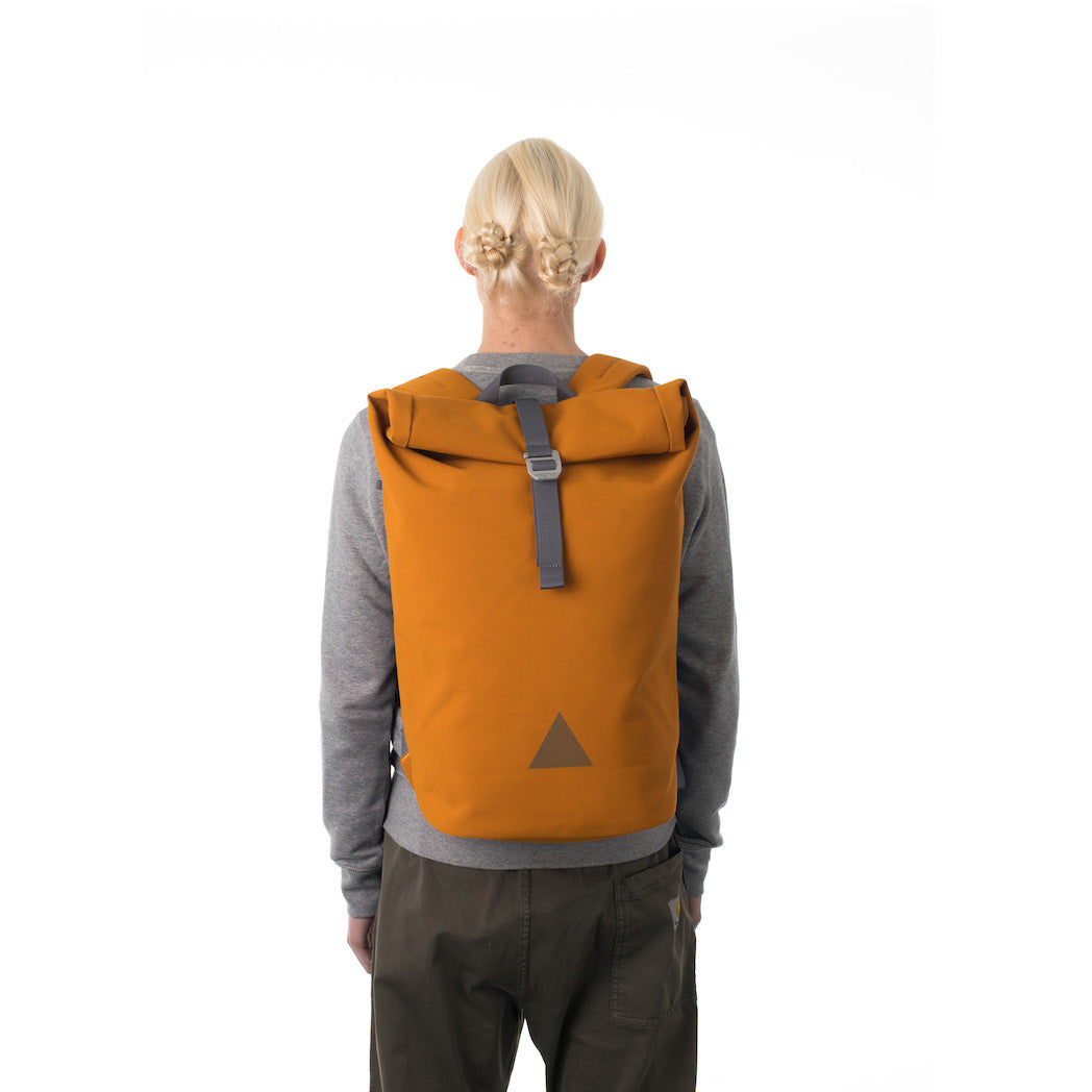 Man carrying orange waterproof rolltop backpack.