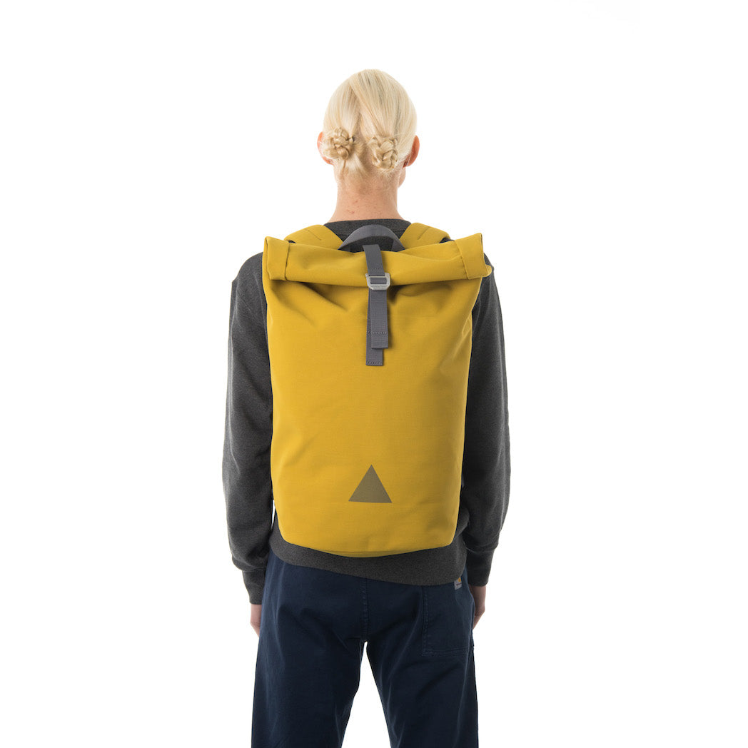 Woman carrying yellow waterproof rolltop backpack.