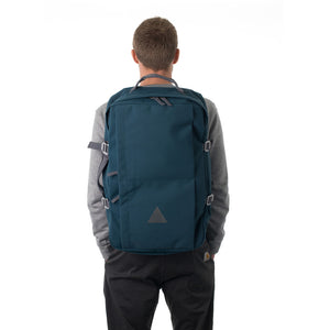 Man carrying blue canvas travel backpack.