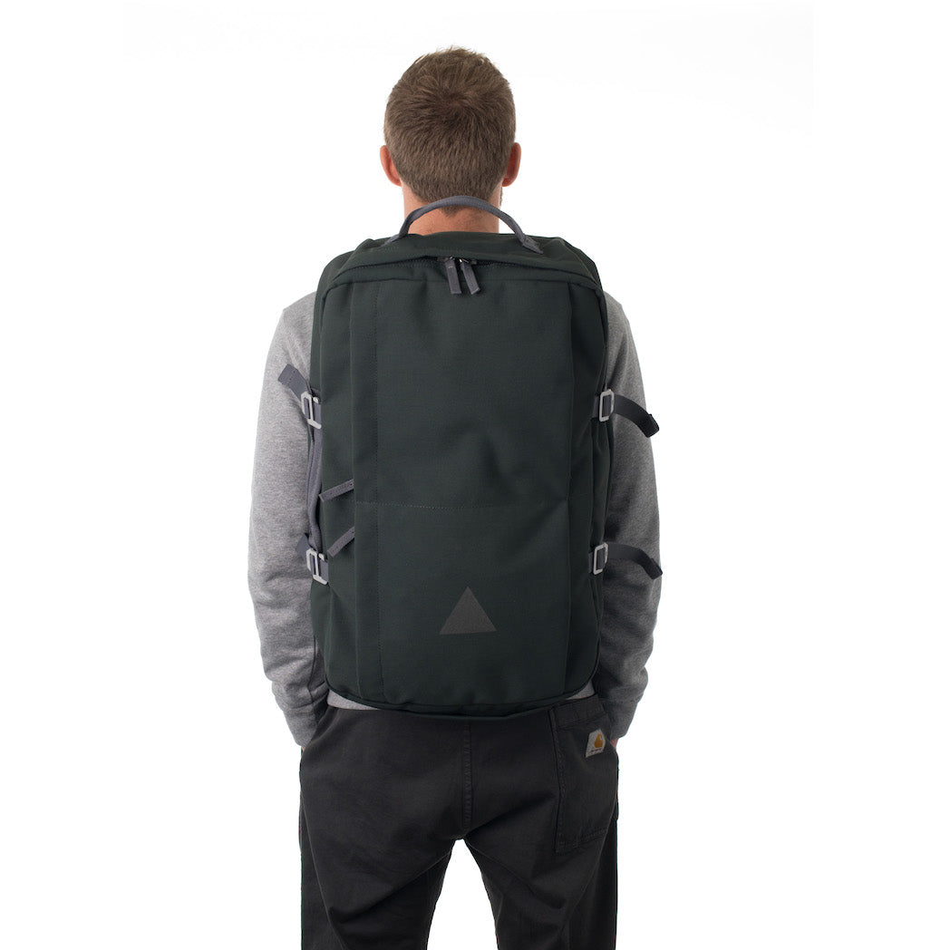 Man carrying grey canvas travel backpack.