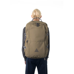 Woman carrying khaki canvas travel backpack.