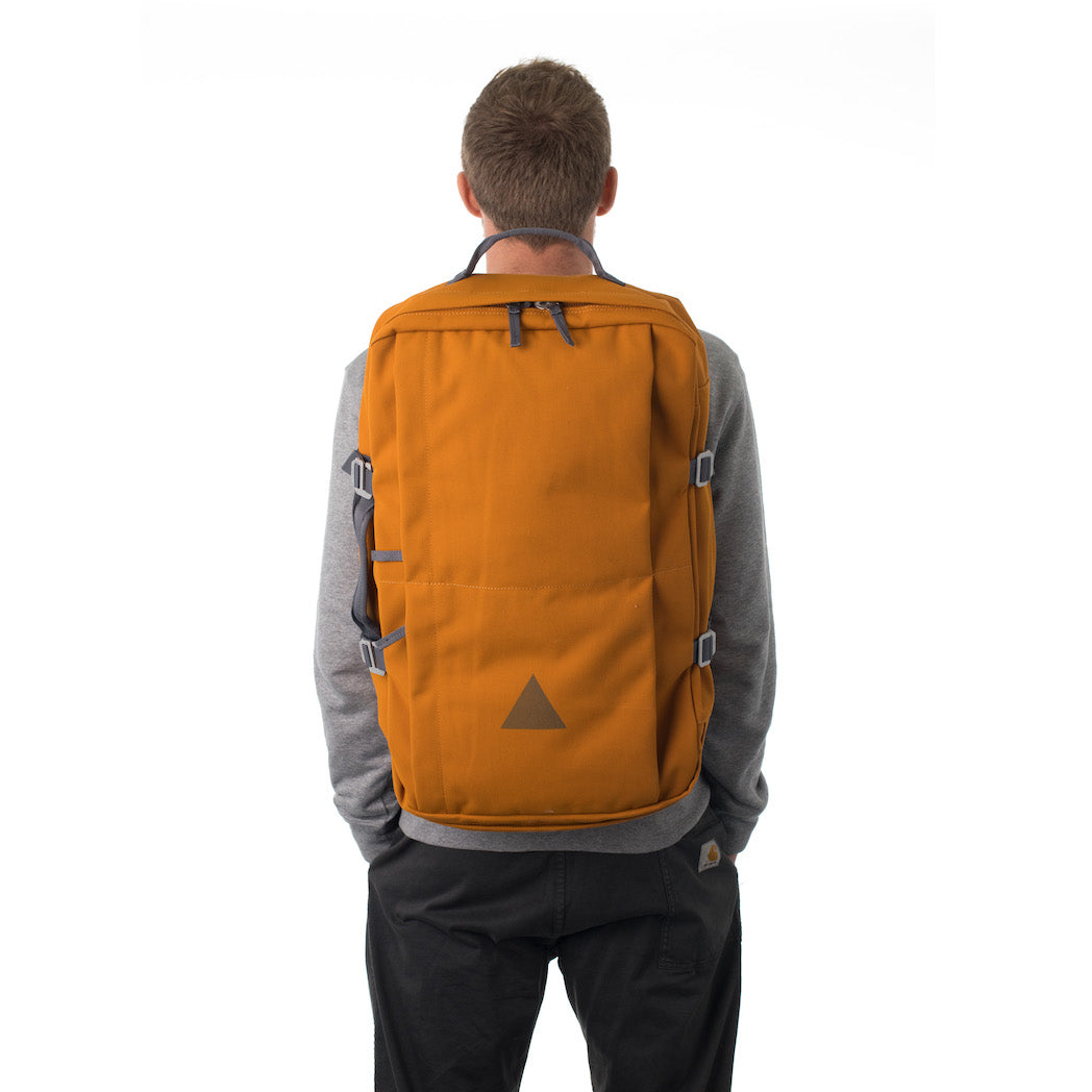 Man carrying orange canvas travel backpack.