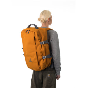 Woman carrying orange travel backpack.