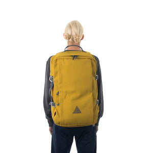 Woman carrying yellow canvas travel backpack.