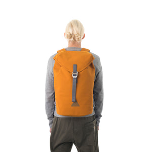 Woman carrying orange waterproof flap backpack.