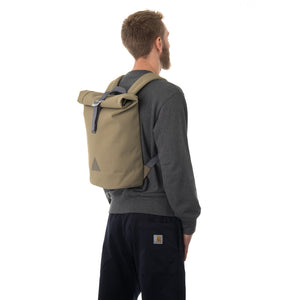 Man carrying khaki rolltop backpack.
