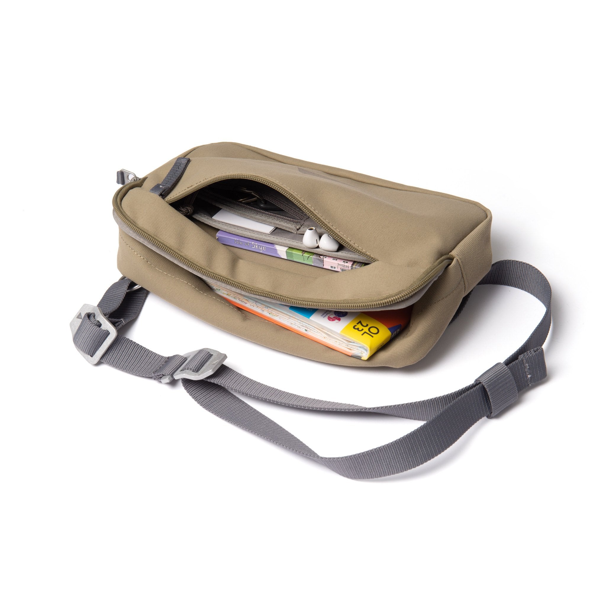 Khaki shoulder bag with front zip open showing map and guidebooks.