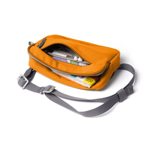 Orange shoulder bag with front zip open showing map and guidebooks.
