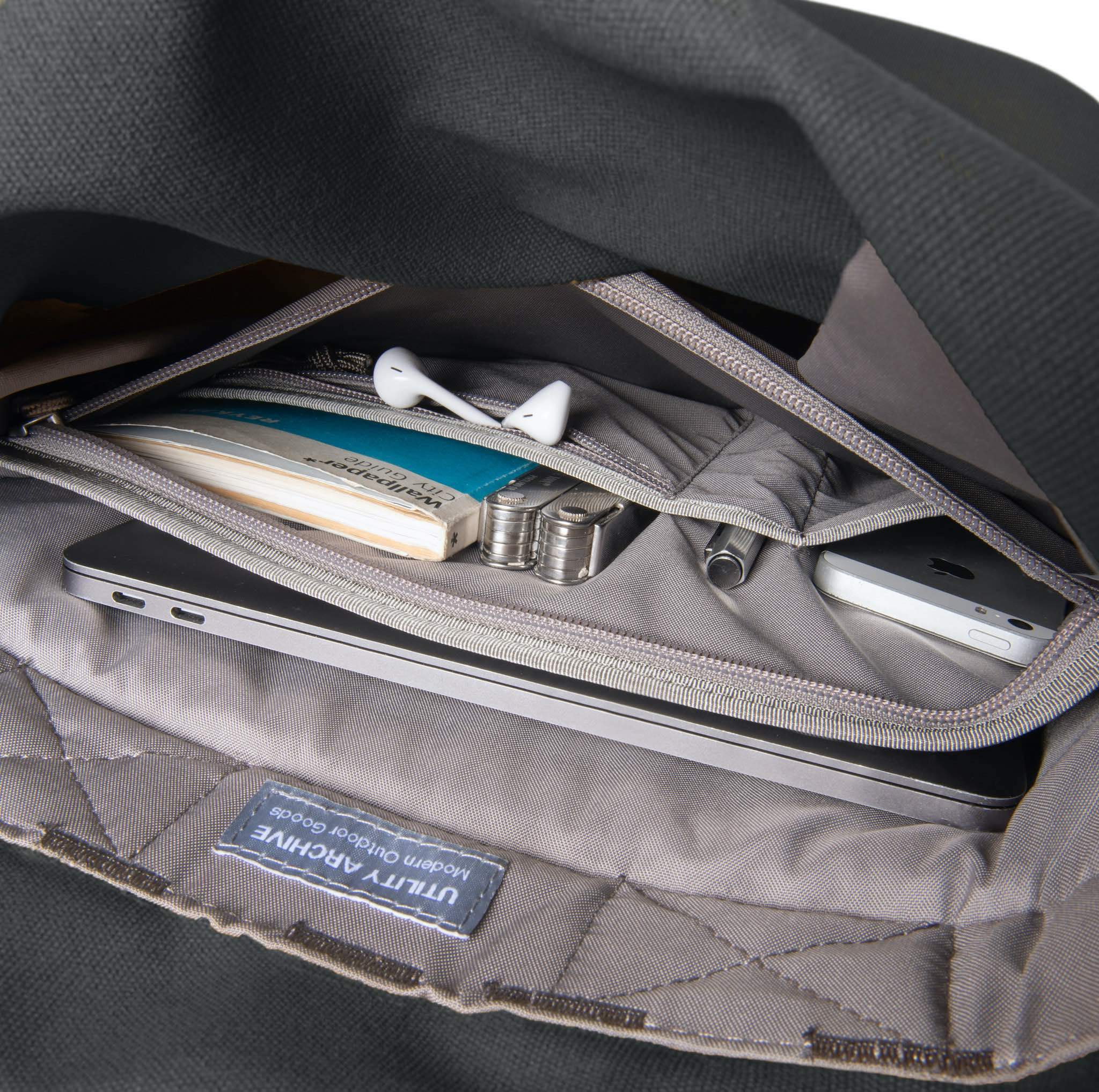 Grey backpack organiser pocket with guidebook and earphones.