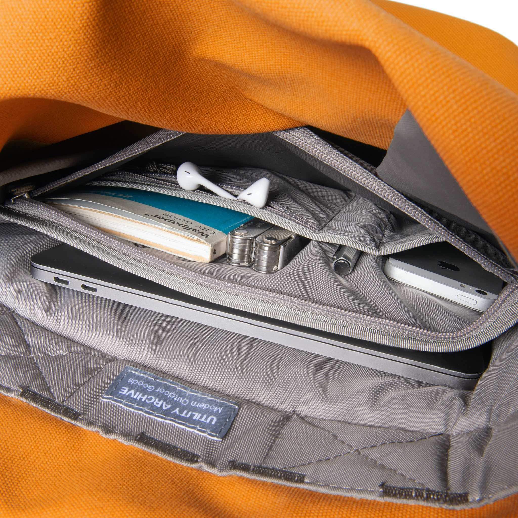 Orange backpack interior organiser pocket with guidebook and earphones.