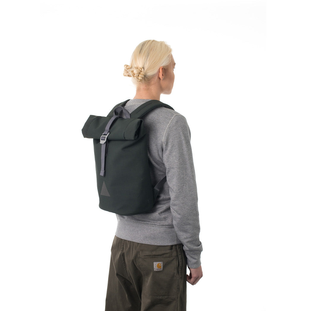 Woman carrying grey rolltop backpack.
