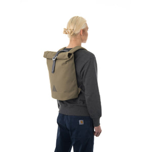 Woman carrying khaki rolltop backpack.