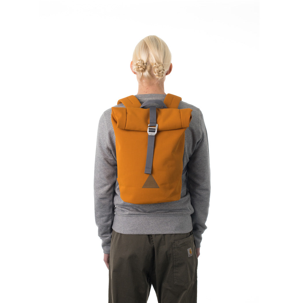 Woman carrying orange waterproof rolltop backpack.