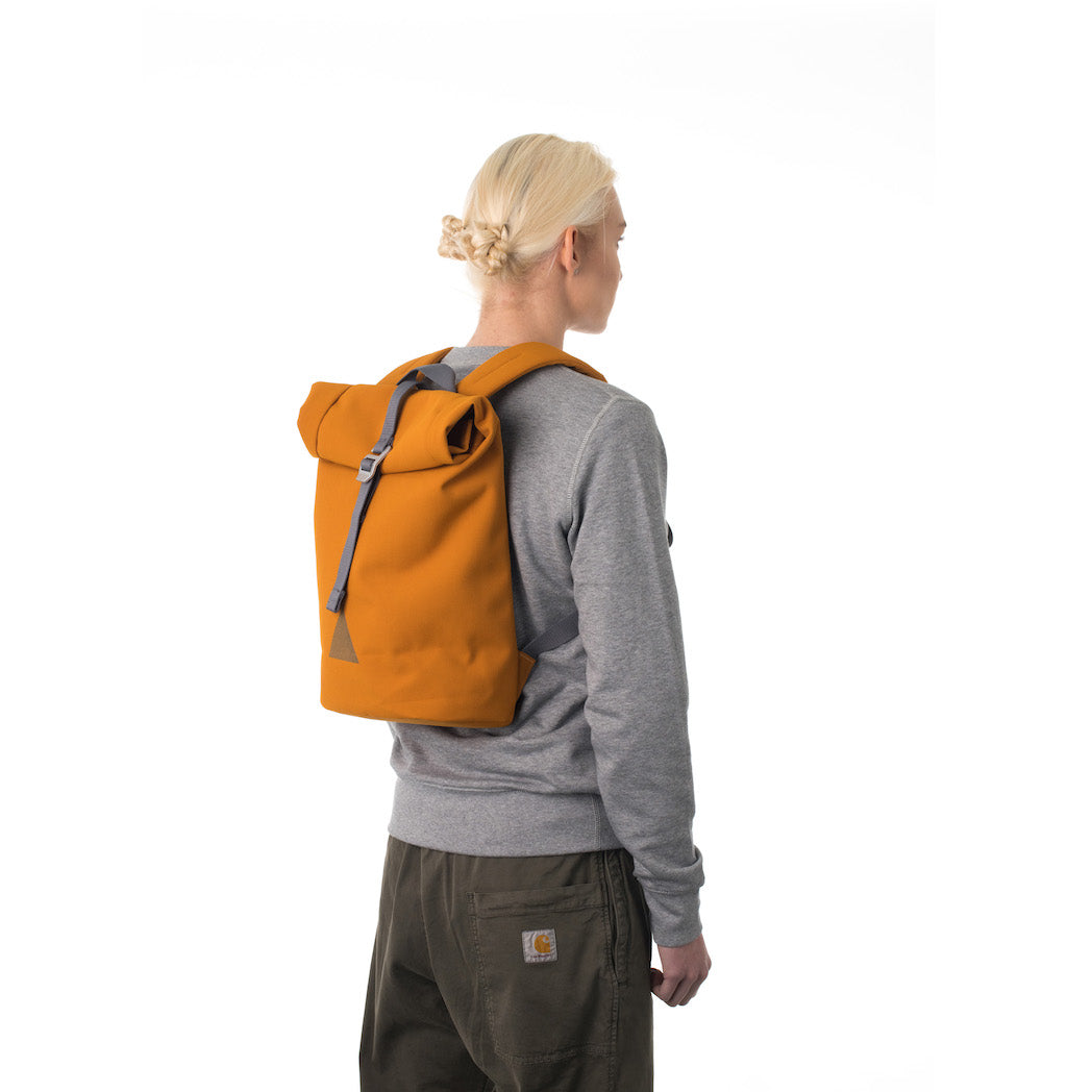 Woman carrying orange rolltop backpack.