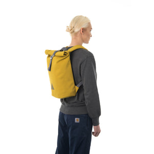 Woman carrying yellow rolltop backpack.