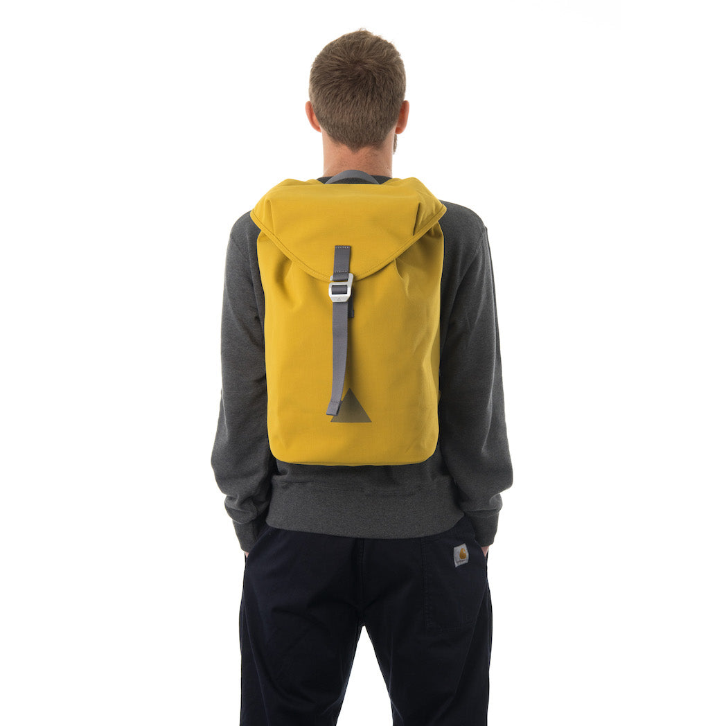 Man carrying yellow waterproof flap backpack.