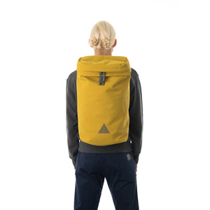 Woman wearing large yellow backpack with triangle logo.