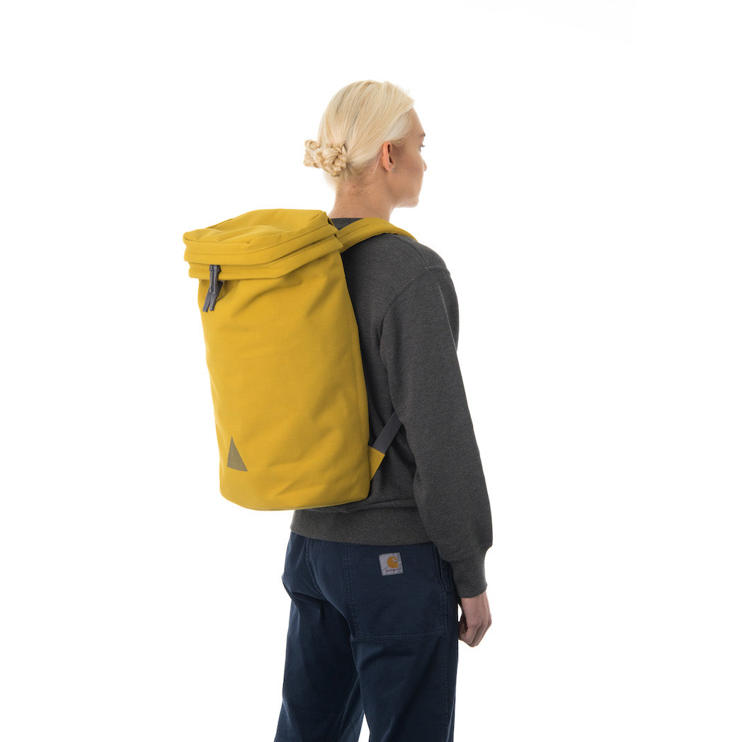Woman wearing large yellow canvas backpack.